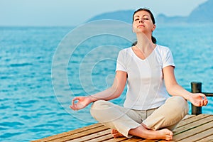 Girl sitting on a pier in lotus position