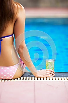 Girl sitting at poolside with beer glass