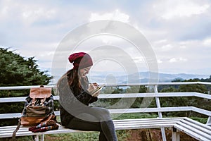 The girl is sitting relaxing at the natural mountain viewpoint and writing a record of her winter travel. smiled happy writing a