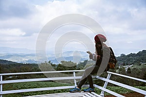 The girl is sitting relaxing at the natural mountain viewpoint and writing a record of her winter travel. smiled happy writing a