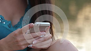 Girl Sitting on the River Bank With the Phone