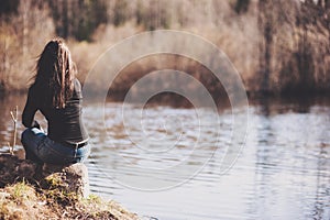 Girl sitting on a rock on the Bank of river forest