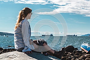 Girl Sitting on a Rock at Kitsilano Beach in Vancouver, Canada