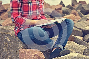 Girl sitting on rock and reading a book