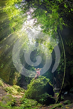 A girl sitting on a rock at Tukad Cepung Waterfall in bali 2