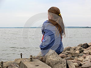 A girl sitting on the rocks by the beach