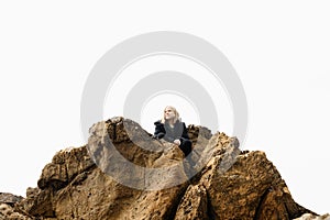 A girl sitting on rocks looking at view