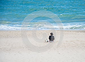 The girl sitting on the sand looks at the sea