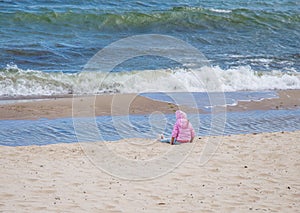 The girl sitting on the sand looks at the sea