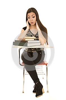 Girl sitting at school desk with overloaded expression