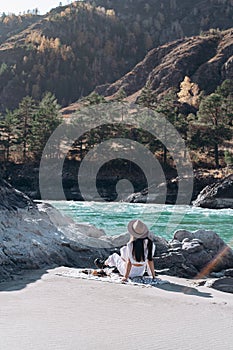 Girl sitting on the shore of a mountain river