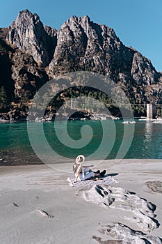 Girl sitting on the shore of a mountain river