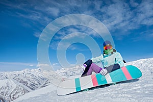 Girl is sitting on the snow with a snowboard board. Winter. The
