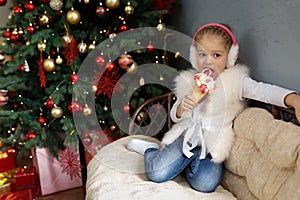 Girl sitting on a sofa and eating sweets on the background of a Christmas tree