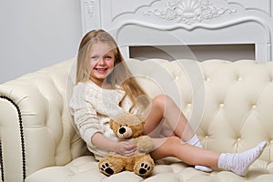 Girl sitting on sofa hugging teddy bear