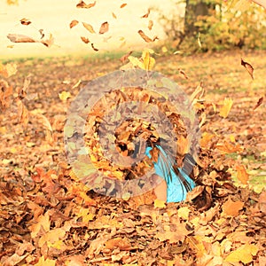 Girl sitting in spate of falling leaves