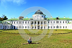 Girl sitting on the splits in the background of a large palace
