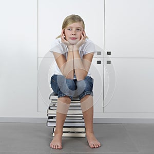 Girl sitting on a stack of books