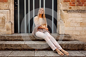 Girl sitting stairs medieval Romanesque door evening sun