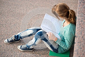 Girl sitting on stairs and reading note