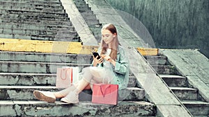 A girl sitting on the stairs on the street communicates on social networks.