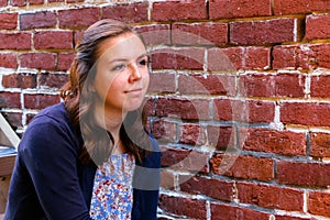 Girl Sitting on Stairway, Next to Red Brick Wall