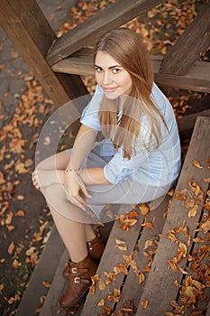 Girl sitting on the steps of the wooden porch, autumn season
