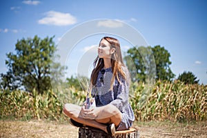 Girl sitting on a stump in a meadow. Meditacion