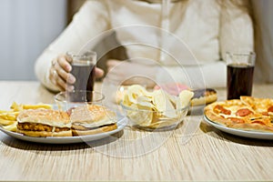 The girl is sitting at the table and eating fast food.