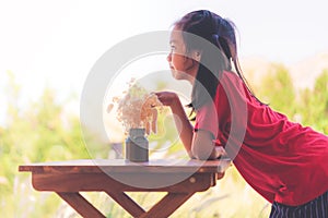 Girl sitting on table with a jar of flower for children love nature concept