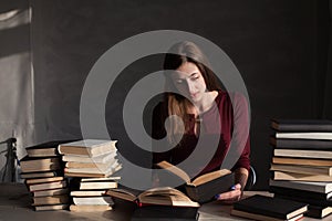 The girl sitting at the table reading a lot of books