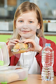 Girl Sitting At Table In School Cafeteria Eating Healthy Packed