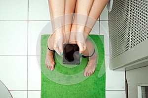 Girl sitting on the toilet holding a smartphone in her hands, top view. The concept of problems with the chair, intestines,