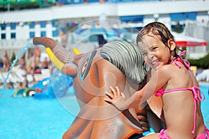 Girl sitting on toy elephant near pool