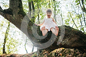 Girl sitting on a tree. foot. Played with their feet