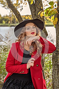 The girl is sitting on a tree by the lake