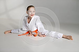 The girl is sitting on the twine, a cheerful karate child on a white background