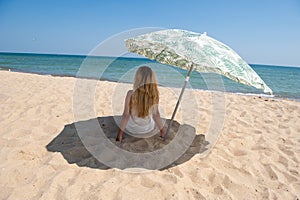 Girl sitting under a beach umbrella