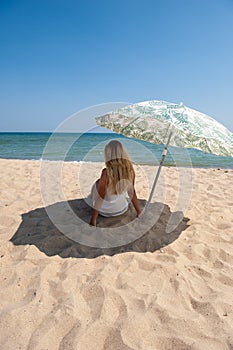 Girl sitting under a beach umbrella