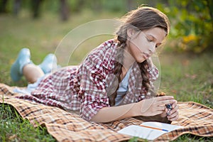 The girl sitting under the tree and wrote in Notepad