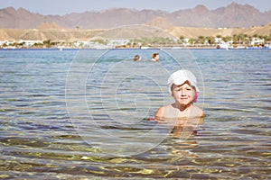 Girl sitting in water in middle of beach