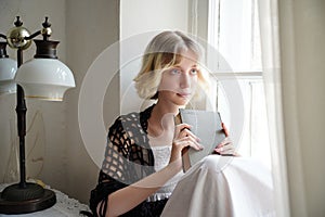 girl sitting by the window with a book, retro style