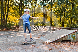 A girl skates up the ramp on a skatepark with the longboard