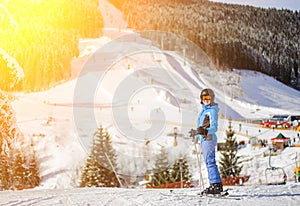 Girl skier against ski slopes and ski-lift on background