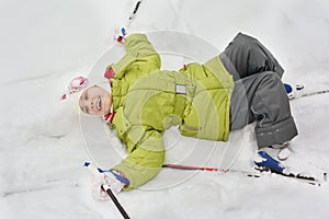 Girl with skiing, sticks lie on snow