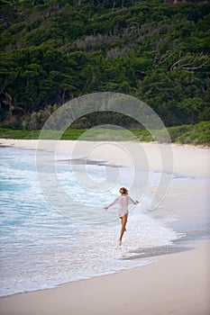 Girl skipping along the shore,seychelles.