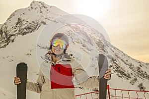 Girl with skis in helmet and mask on the background of mountains toned