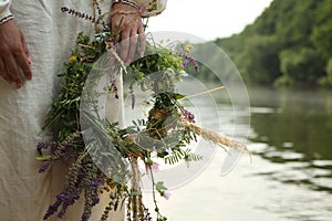 The girl in Slavic clothes with a wreath on the background of the river