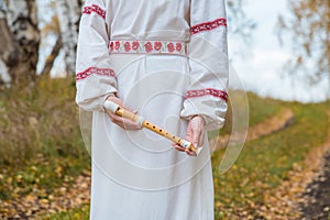 The girl in the Slavic dress holds in her hands a flute in the a