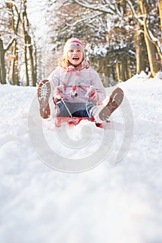 Girl Sledging Through Snowy Woodland